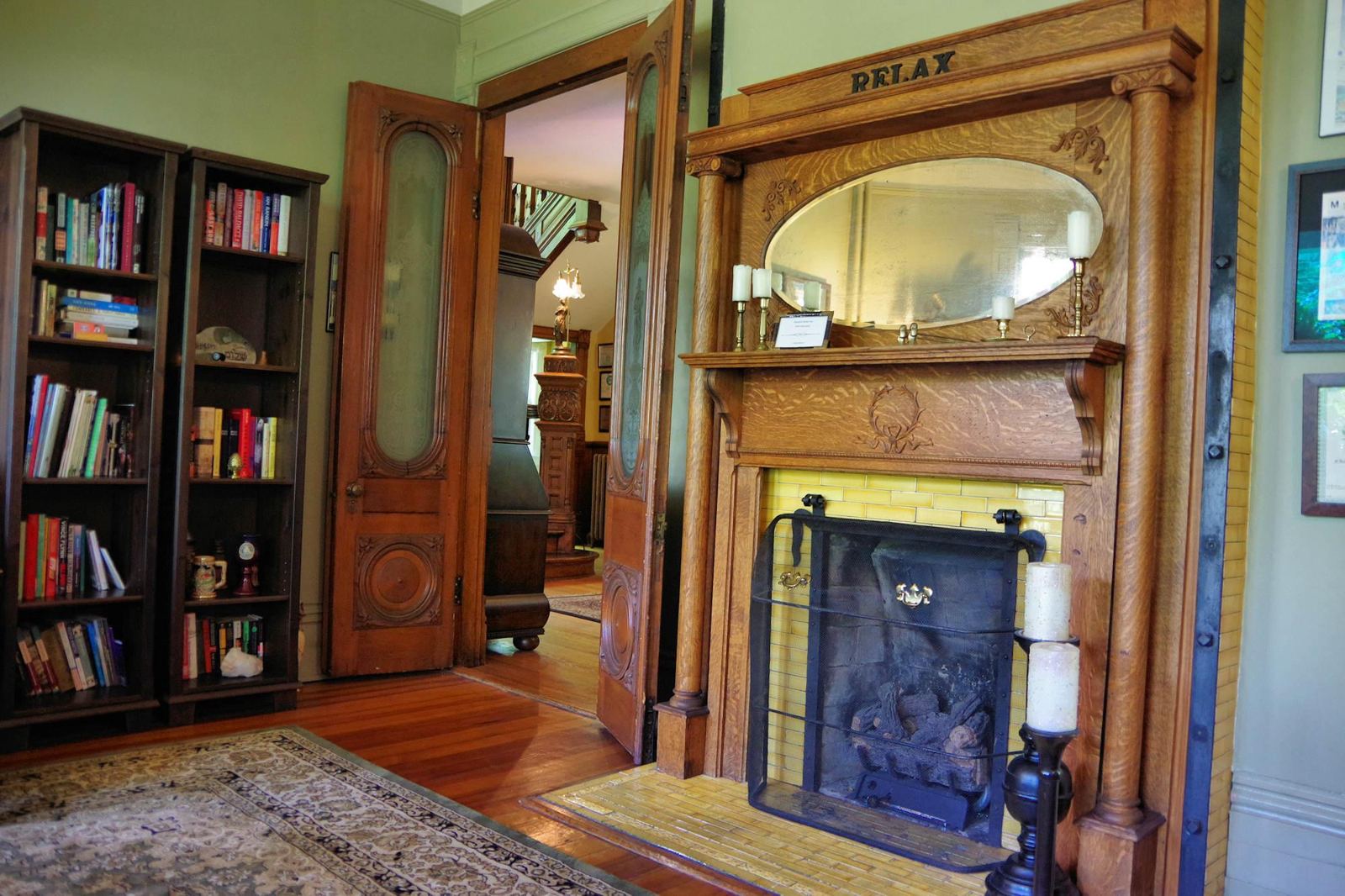 Library with carved oak fireplace, bookshelves and pocket doors