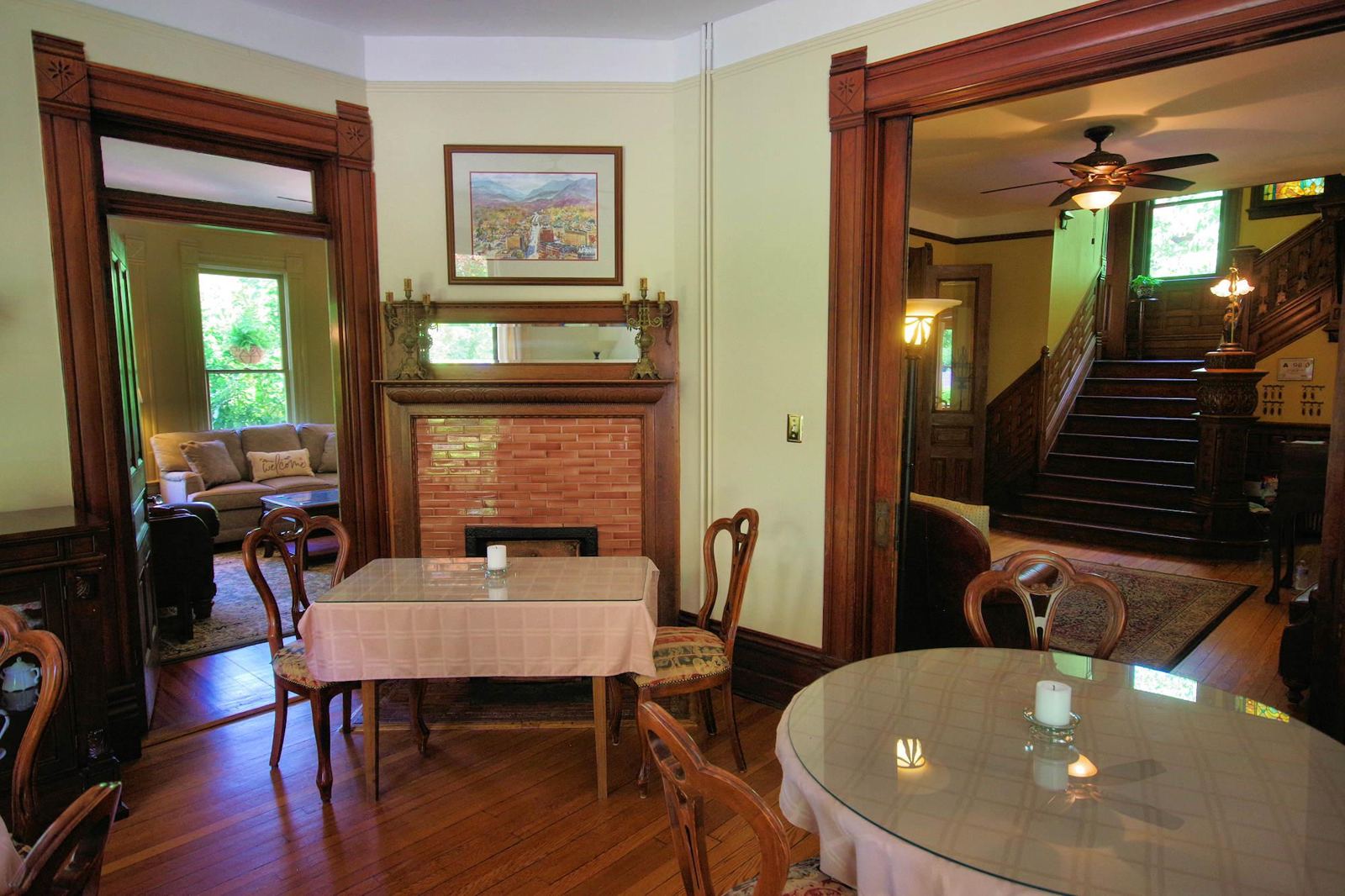 The inn dining room with fireplace, set tables and a view of the grand staircase